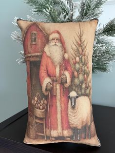 a pillow with a santa clause standing next to a christmas tree and a sheep on it