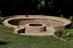 an outdoor fire pit surrounded by grass and flowers