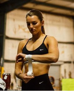 a woman in a black sports bra holding a white wristband