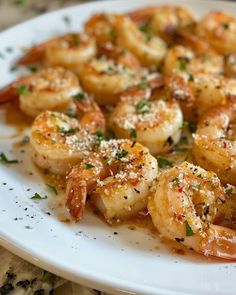 a white plate topped with cooked shrimp and garnished with parmesan cheese