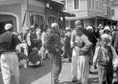 an old black and white photo of people walking down the street