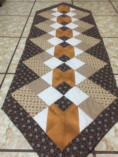 a quilted table runner on the floor with an orange and white striped strip across it