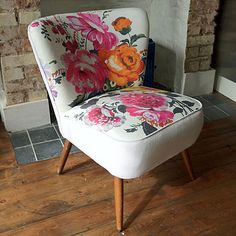 a white chair with flowers on it sitting in front of a brick wall and fireplace