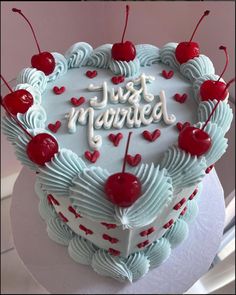 a heart shaped cake with cherries and the words just married written in frosting