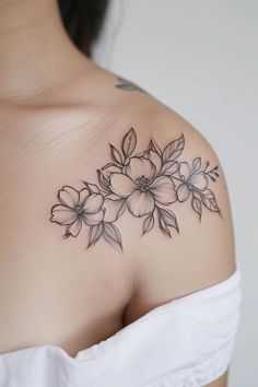 a woman's shoulder with flowers and leaves tattoo on her left side breast area