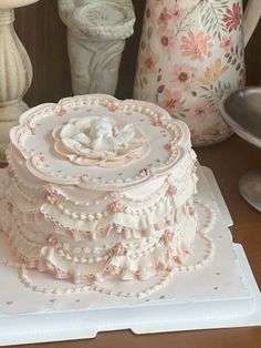 a three tiered cake sitting on top of a white plate next to vases