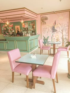 the interior of a restaurant with pastel colored chairs and tables in front of a wall painting