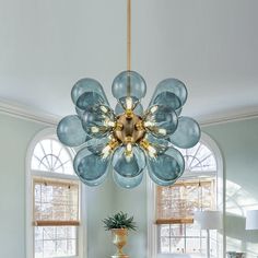 a chandelier hanging from the ceiling in a living room with blue walls and windows