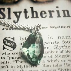 an image of a necklace with a green stone on it and the words slytherin written in english