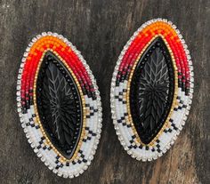 two pairs of beaded earrings sitting on top of a piece of wooden floor next to each other