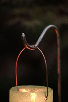 a candle that is sitting on a table with some kind of hook in it's middle