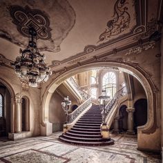 an ornate staircase in the middle of a large building with chandeliers hanging from it's ceiling