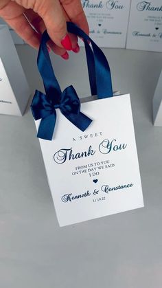 a person is holding a thank card with a blue ribbon and bow on the front