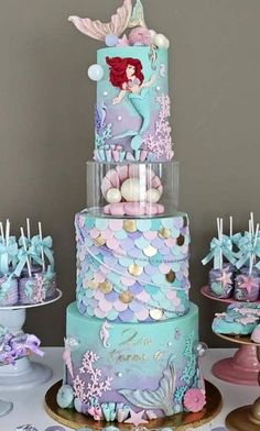 there is a three tiered cake with mermaid decorations on it