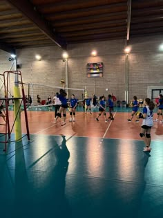 some girls are playing volleyball in a gym