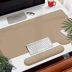 a computer desk with a keyboard, mouse and plant on it in front of a monitor