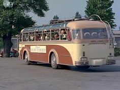 an old bus is driving down the street with people in it's seat area