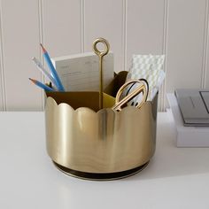 a desk with a pen holder, scissors and other office supplies in it on top of a white table