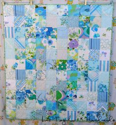 a blue and green patchwork quilt hanging on a wall