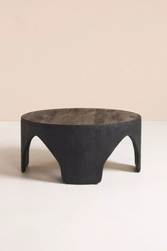 a concrete coffee table with black legs and an oval top, on a white surface