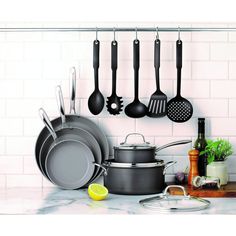 pots and pans hanging on the wall in a kitchen with white tile backsplash