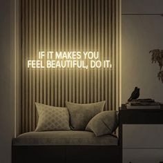 a couch sitting in front of a wall with a neon sign above it that says, if it makes you feel beautiful, do it