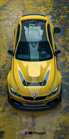 a yellow sports car is parked on the wet ground with its hood up and it's reflection in the rear window