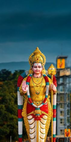 a statue of the god ganesh in front of a building with trees and buildings behind it