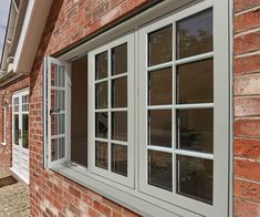 an open window on the side of a red brick building with white trim and glass panes