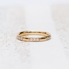 a gold wedding band with five diamonds on it, sitting on a white tablecloth