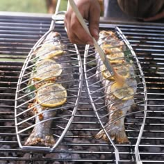 someone is grilling fish with lemon slices on the grill