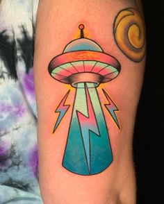 a tattoo on the leg of a person with an alien ship in it's center