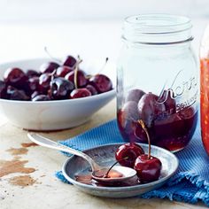 cherries are in a bowl next to a mason jar