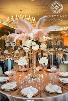 the centerpieces are adorned with pink and white flowers, feathers, and champagne flutes