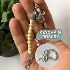 a hand holding a keychain with two charms attached to it next to a plant