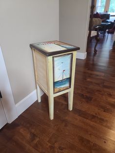 a small wooden table with a painting on it's top and the bottom shelf