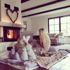 two women sitting on the floor in front of a fire place with their laptops