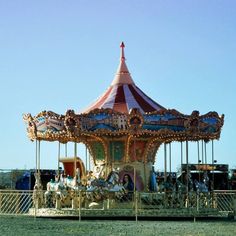 an old fashioned merry go round in the middle of a field with people on it