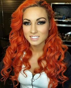 a woman with long red hair is smiling at the camera while wearing an orange wig