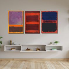 two abstract paintings hang on the wall next to a white shelf with books and plants