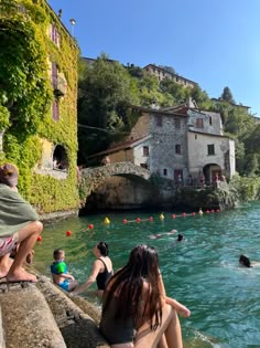 people are sitting on the edge of a body of water