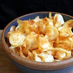 a blue bowl filled with potato chips on top of a wooden table