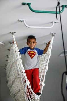 a young boy standing in a hammock