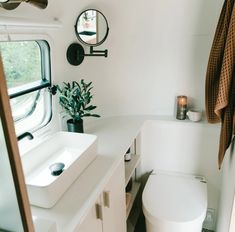 a white toilet sitting next to a sink in a bathroom under a mirror and towel rack