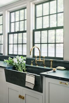 a kitchen with white cabinets and black counter tops, gold faucets and brass fixtures