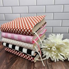 a stack of books sitting on top of a wooden table next to a white flower