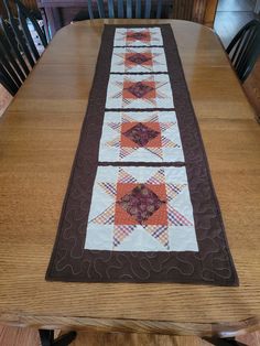 the table runner is made from quilts and has an orange, purple, and white design on it