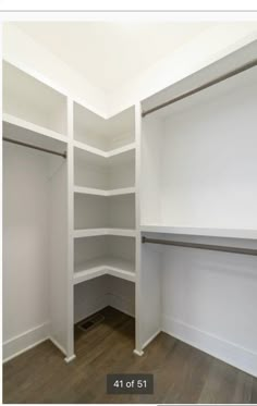 an empty walk in closet with white shelving and wood flooring on the walls