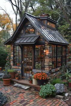 a small house with lots of windows and plants on the front porch, surrounded by brick pavers