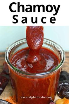 a spoon dipping sauce into a jar filled with fruit